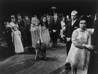 a bunch of spooky people stare at a camera in the hall of a haunted house in a still from the tv show dark shadows