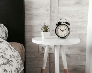 a black and white clock sat in a white bedside table in a white room