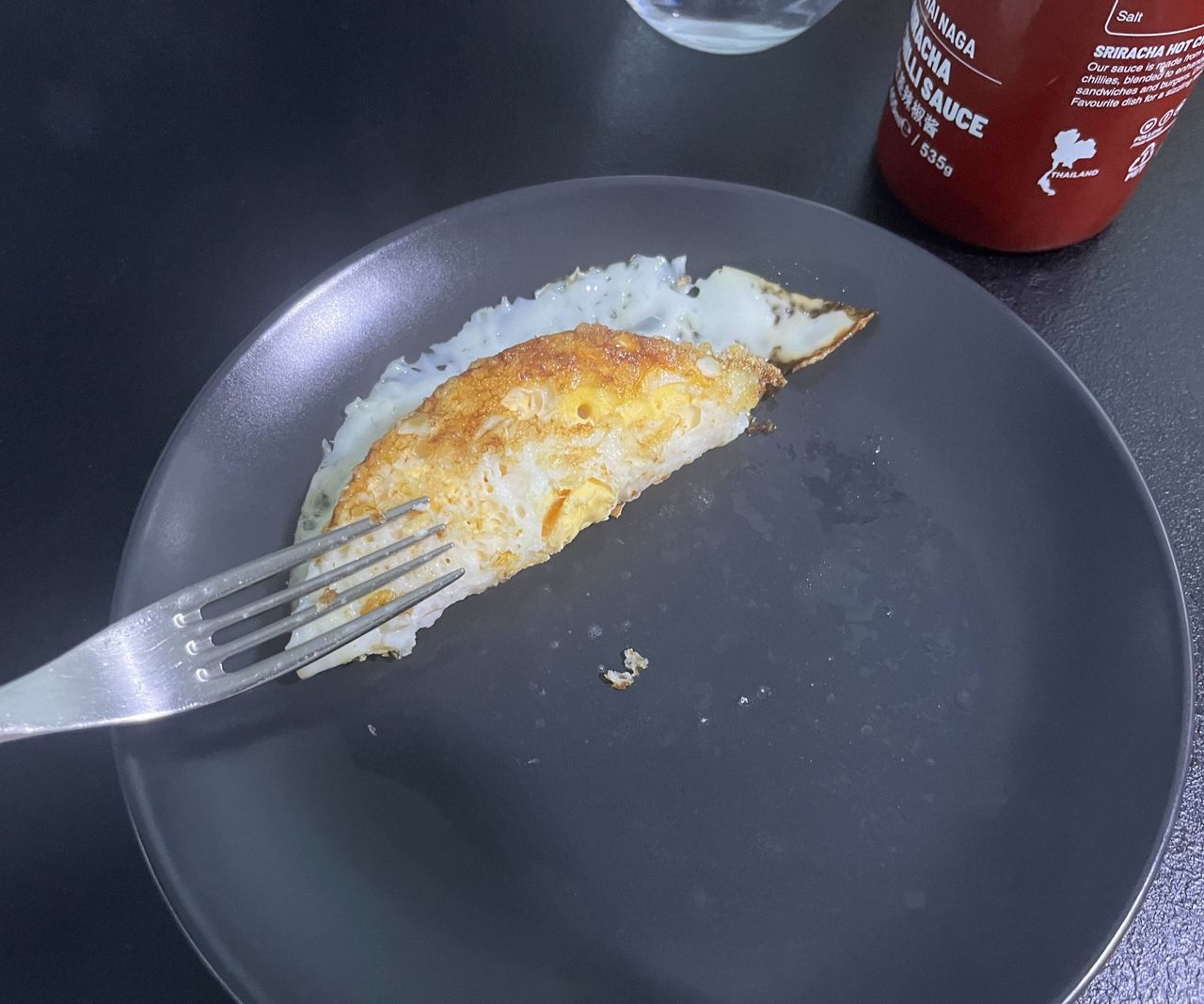 The crispy base of a fried egg on a grey plate .