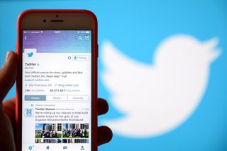 Twitter on a smartphone with the Twitter logo in the background.