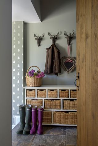 tiny boot room with stag hooks baskets and wallpaper