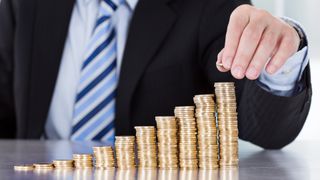 Close-up of a businessman's hand stacking coins in a pile