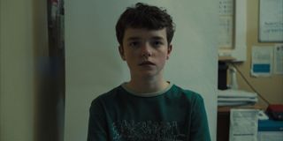 Owen Cooper as Jamie Miller in Adolescence wearing a tshirt sitting in a police station