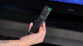 the sony ht-s100f or sony ht-sf150 in uk, a black soundbar with buttons on the top, a remote, photographed with a panasonic TV