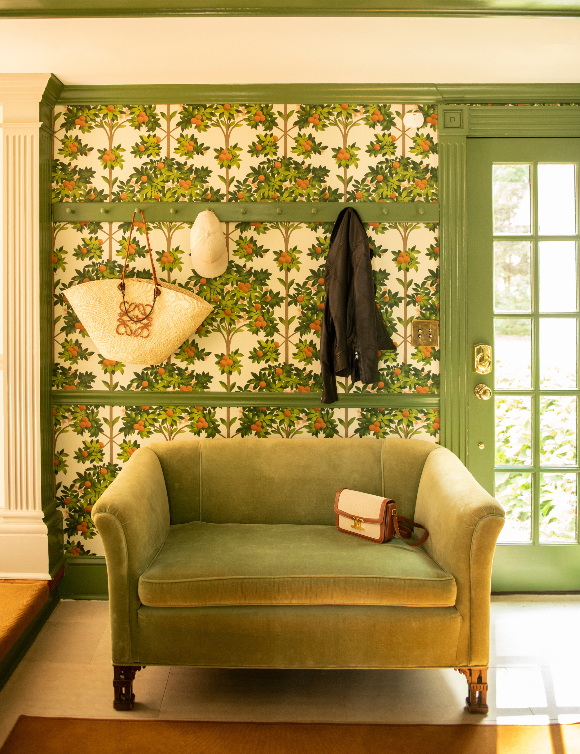 Nicole Fisher-designed entryway featuring orange grove wallpaper and a lush green loveseat