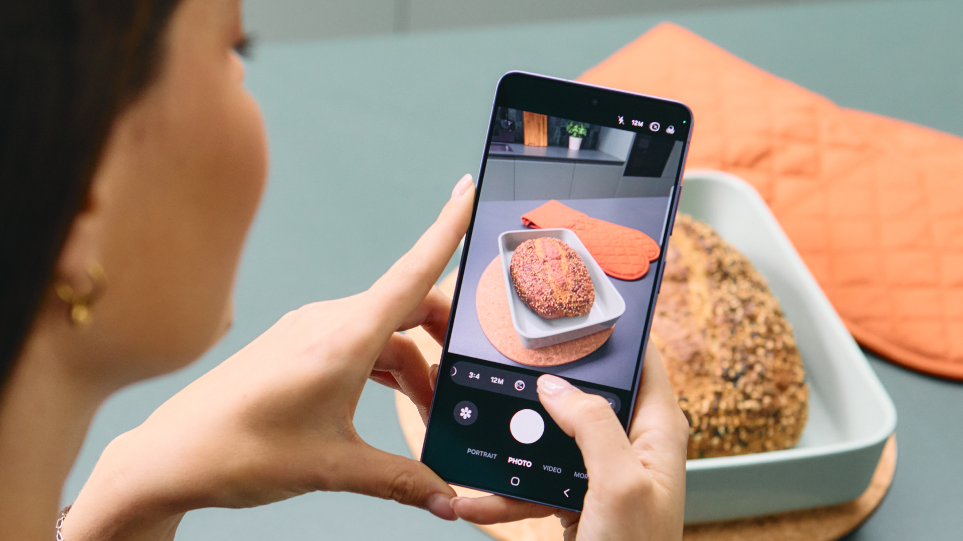 A woman takes a photo of a loaf of bread using a Samsung Galaxy S26 Ultra 