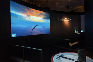 visitors pilot a flying pterosaur at the exhibit