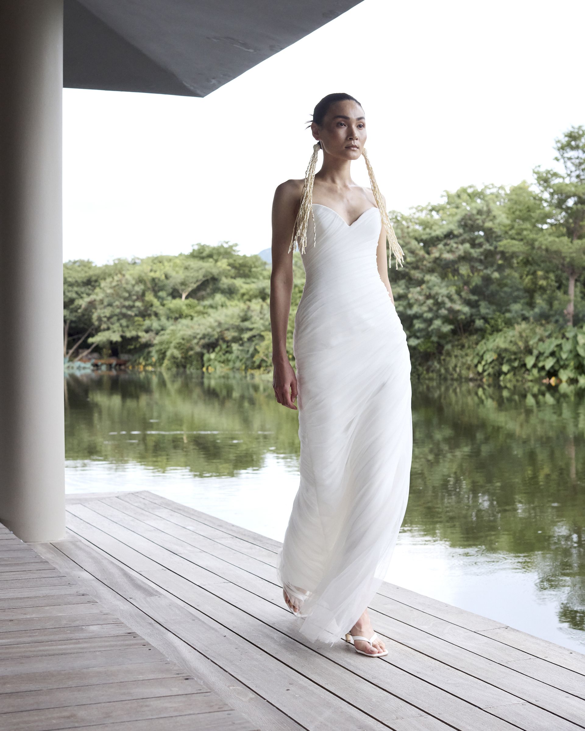 A woman wears a gown with a sweetheart neckline and long straw earrings.