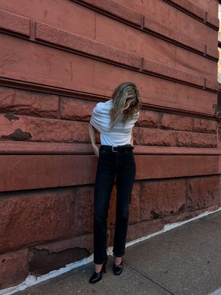 Eliza Huber wearing a cream knit top, a black belt, black Citizens of Humanity Zurie jeans, and black shoes.