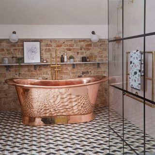 Free standing copper bathtub in bathroom with printed tile floor