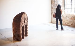 A brick sculpture appearing like a round tower with a domed roof, cut in half vertically