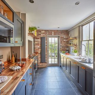 kitchen with grey cupboards on grey tiles leading to back door with a view of the garden