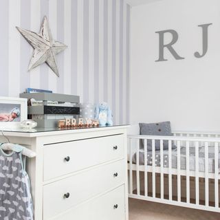 Nursery with grey striped wallpaper and personalised wooden letters on white wall