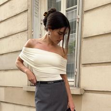 Ilirida Krasniqi wearing an off-the-shoulder cream ruched knit top with a gray pencil skirt. 