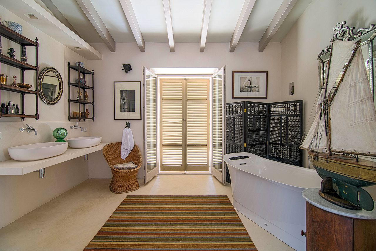 bathroom with twin basins and bathtub with dark screen and shutters