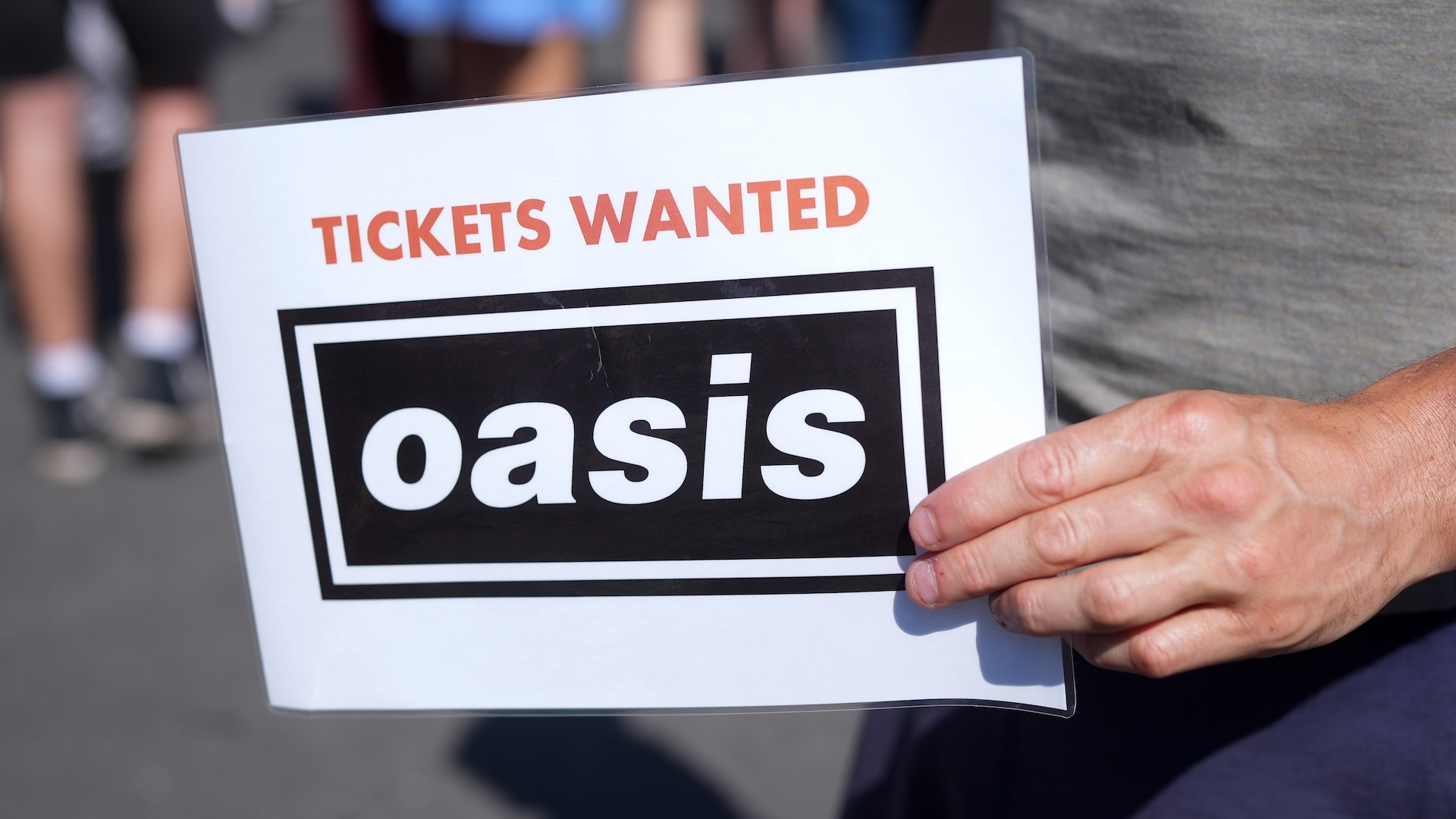 Photo of a hand holding a sign asking for Oasis Tickets - laminated 