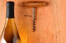 Bottle of wine and corkscew on wooden background