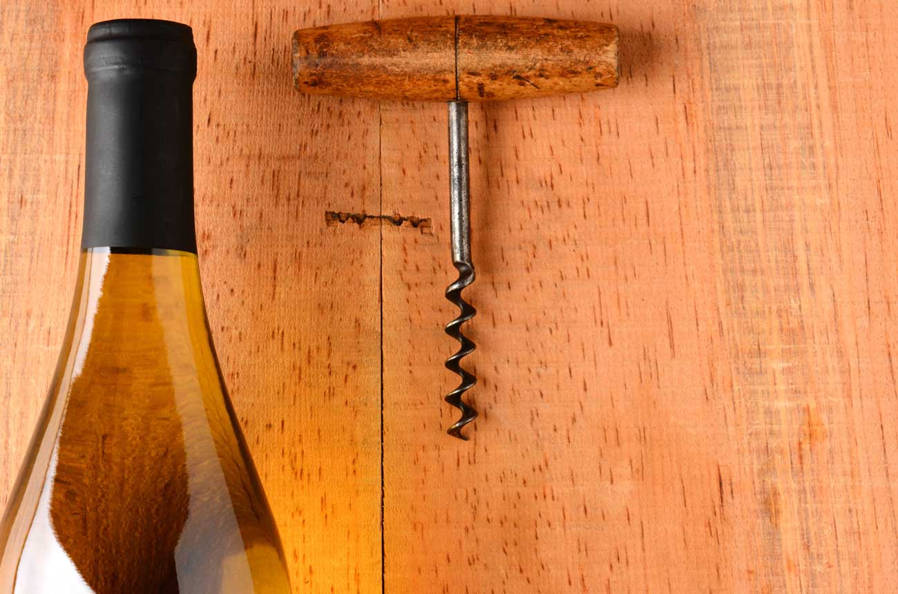 Bottle of wine and corkscew on wooden background