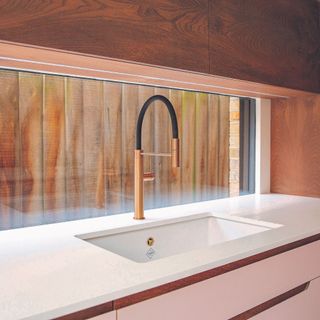 Metallic tap with window splashback on pink kitchen unit