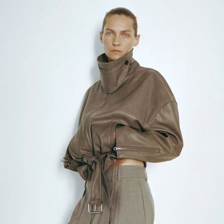 Woman wears leather-look jacket and tailored trousers