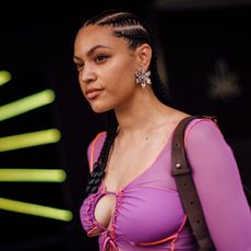 woman in a purple sweater with braids walking into the sun
