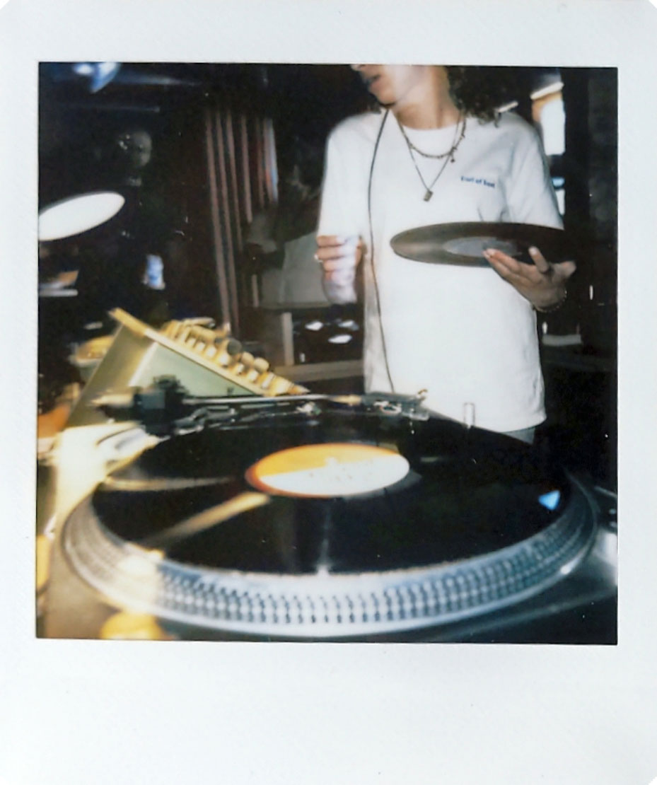 Digitized instant photo taken with the Fujifilm Instax SQ40 of DJ indoors in darkly lit bar