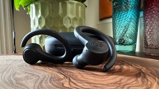 JLab Go Air Sport earbuds on a table in front of the charging case