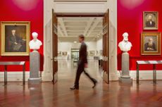 Blurred image of a man walking in an art museum.