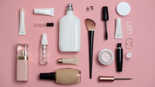 a collection of beauty and skincare products layed out on a pink background