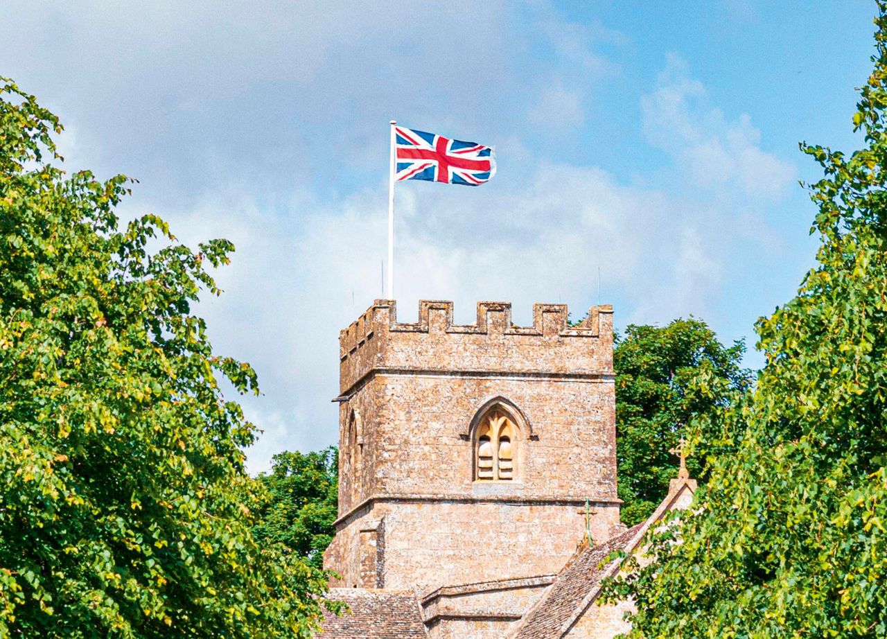 The Union Flag flies above the Norman church of St Michael and All Angels in the Cotswold village of Guiting Power.