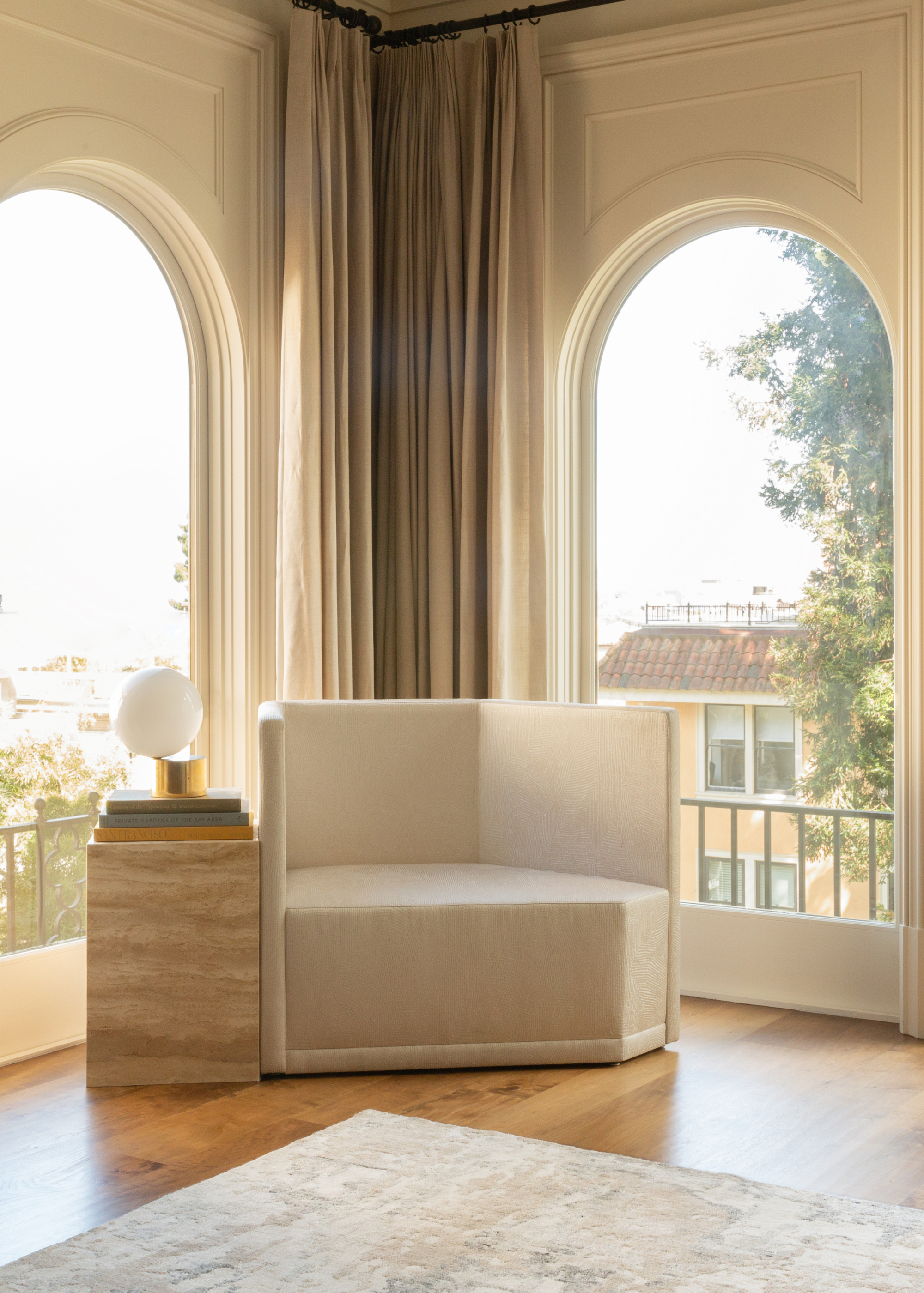 A bright room corner with a wide white sofa chair, a stone table and a lamp