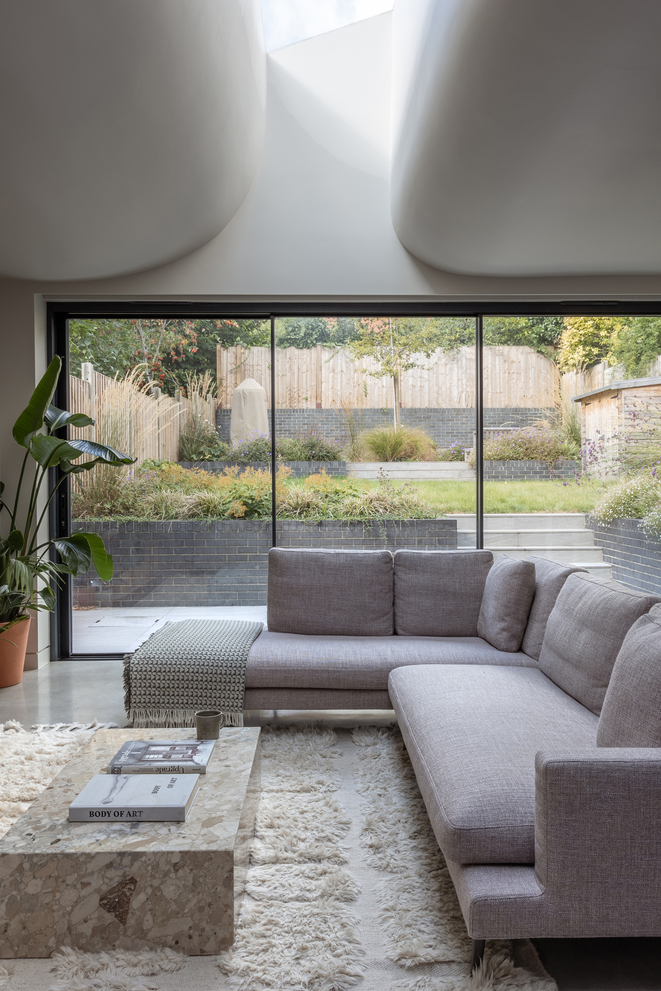 Living area with rooflight, grey L-shaped sofa and stone coffee table