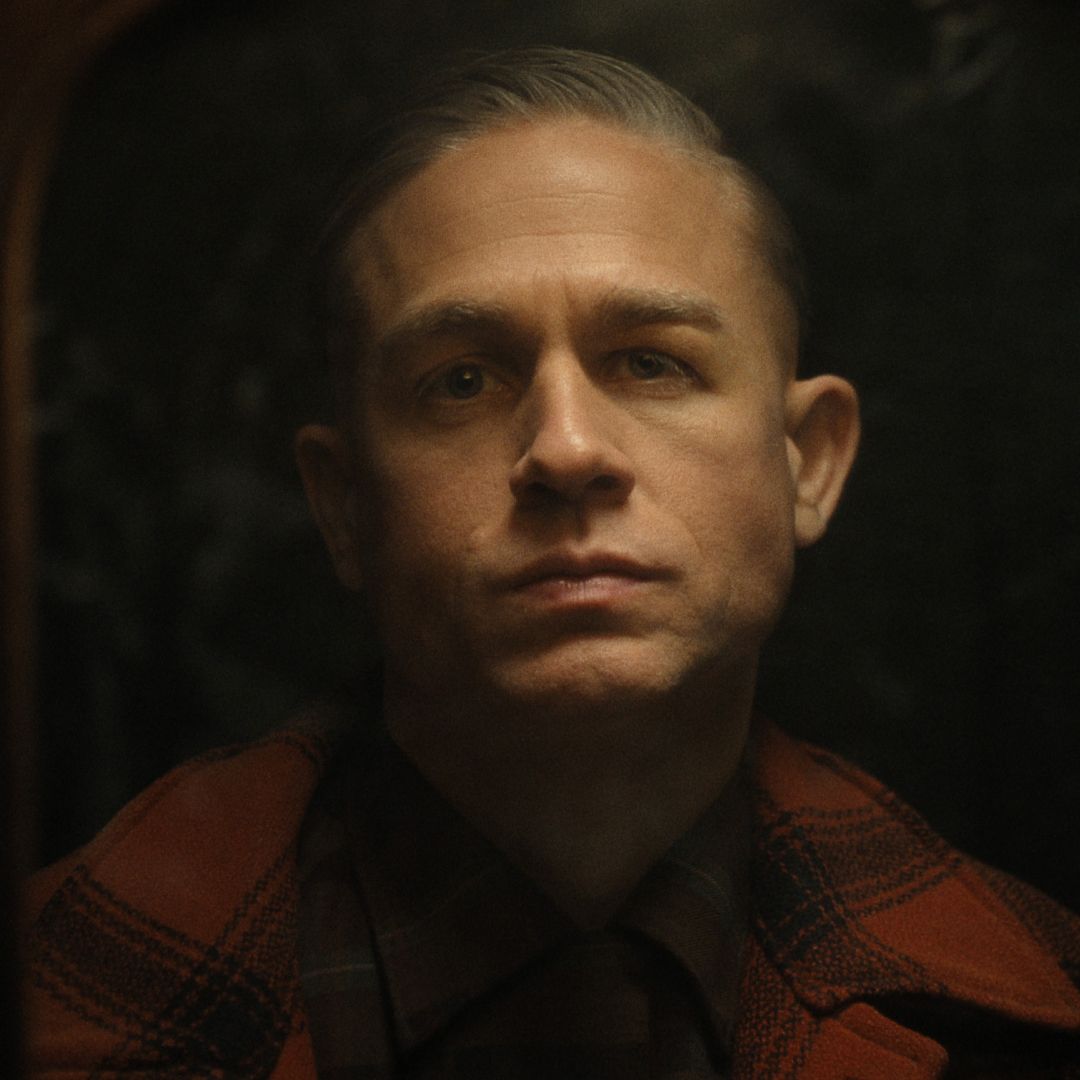 charlie hunnam as ed gein wearing a plaid shirt looking into the camera in monster