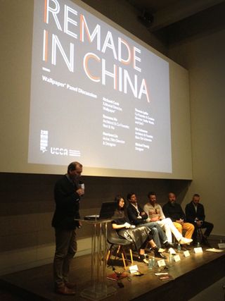 Five people are sitting on chairs on a stage while another stands, giving a presentation on "Remade in China"