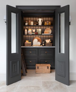 A grey pantry with downlighting kitchen lighting ideas on the shelves inside.