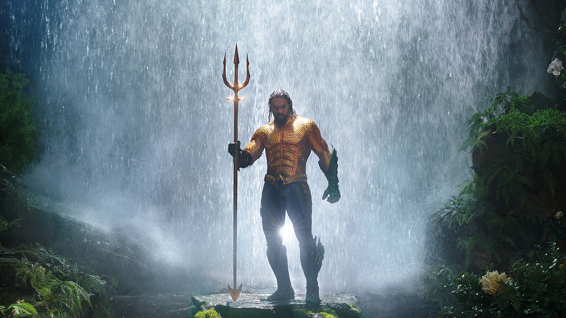 Jason Momoa's Aquaman emerges from a waterfall with his trident and in his classic comic book costume