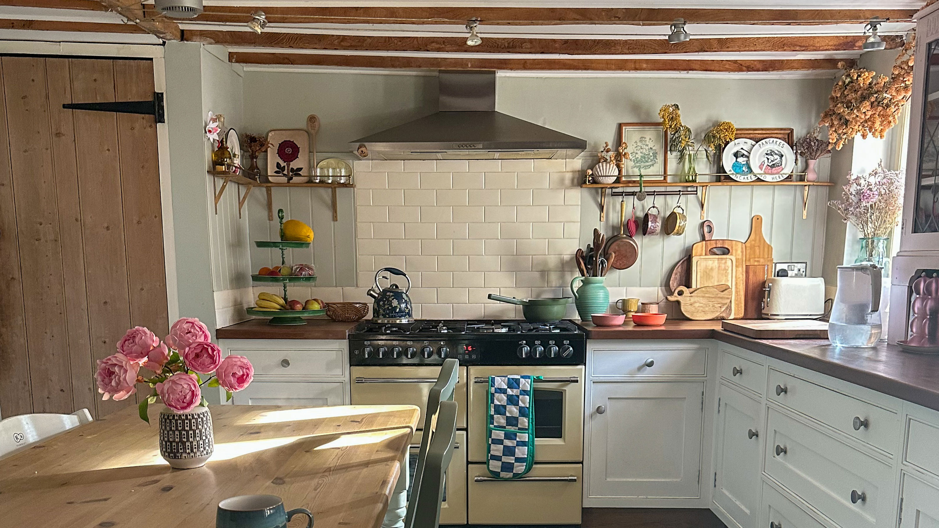 Country kitchen with wooden beams, range oven, wooden countertops and tiled splashback