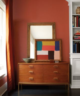 A cinnamon colored room with a vanity and bookshelf