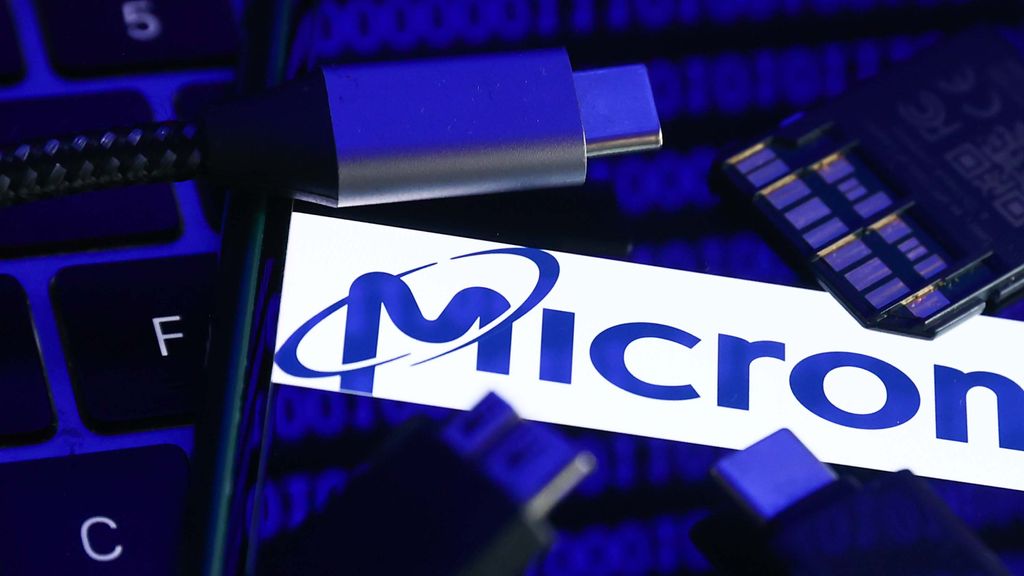 Micron logo displayed on a phone screen with a binary code reflected on it, a laptop keyboard, a memory card, an adaper and cables are seen in this illustration photo taken in Krakow, Poland on January 30, 2023.