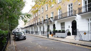 Side perspective, showing a row of houses including the street and a car