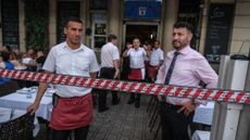 Restaurant workers stand guard over diners during a protest against overtourism in Barcelona