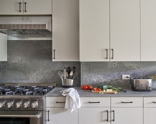 Kitchen with modern flat fronted cabinets and metallic backsplash and range