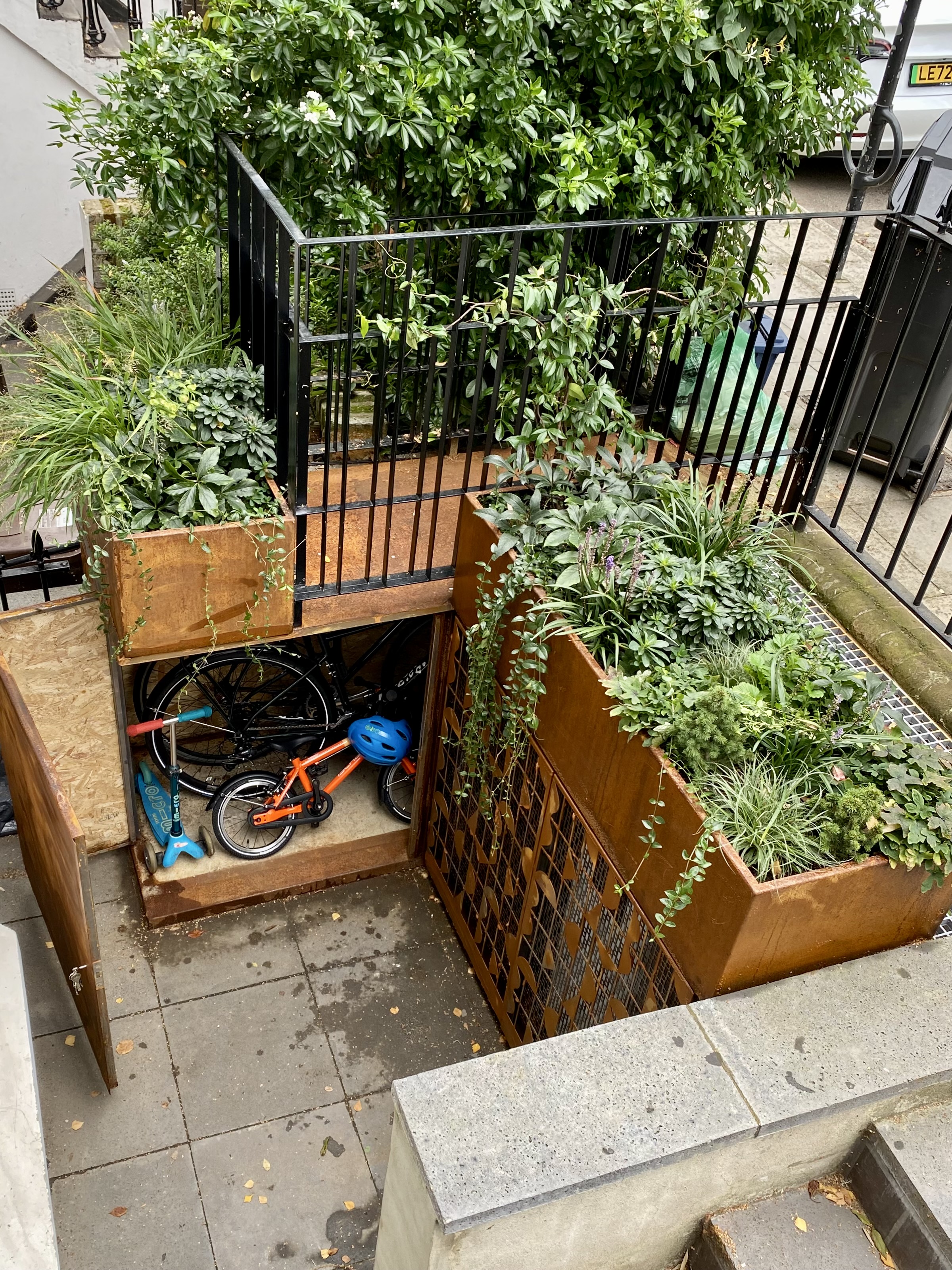 outdoor storage in a front garden for bikes in corten steel planters