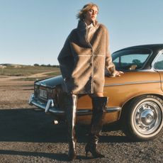 A model wearing a faux fur coat and brown boots, from H&M.