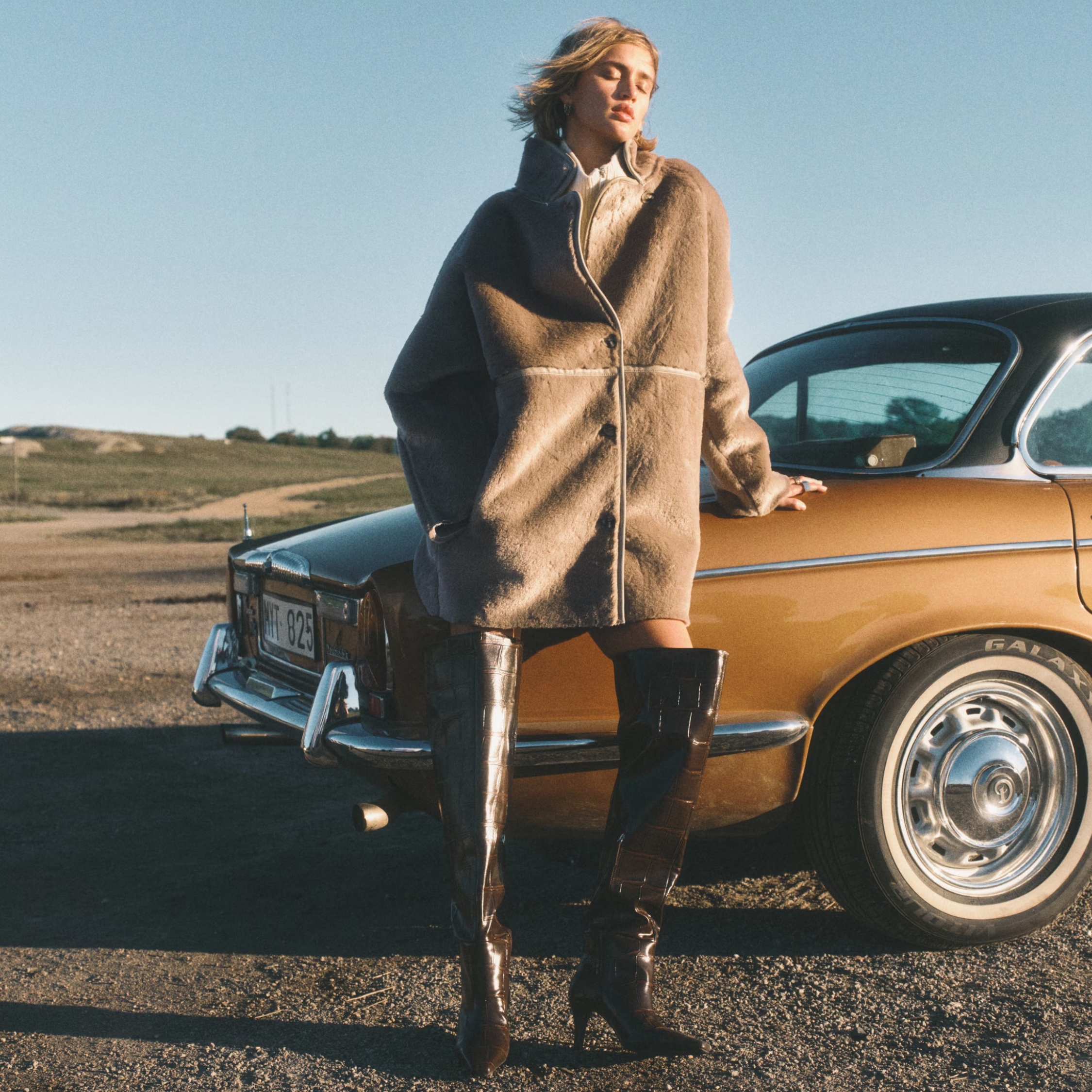 A model wearing a faux fur coat and brown boots, from H&M.