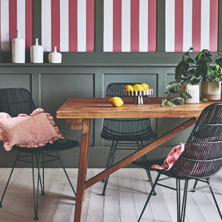 A dining room with green-painted wall panelling and a striped wallpaper in red and white