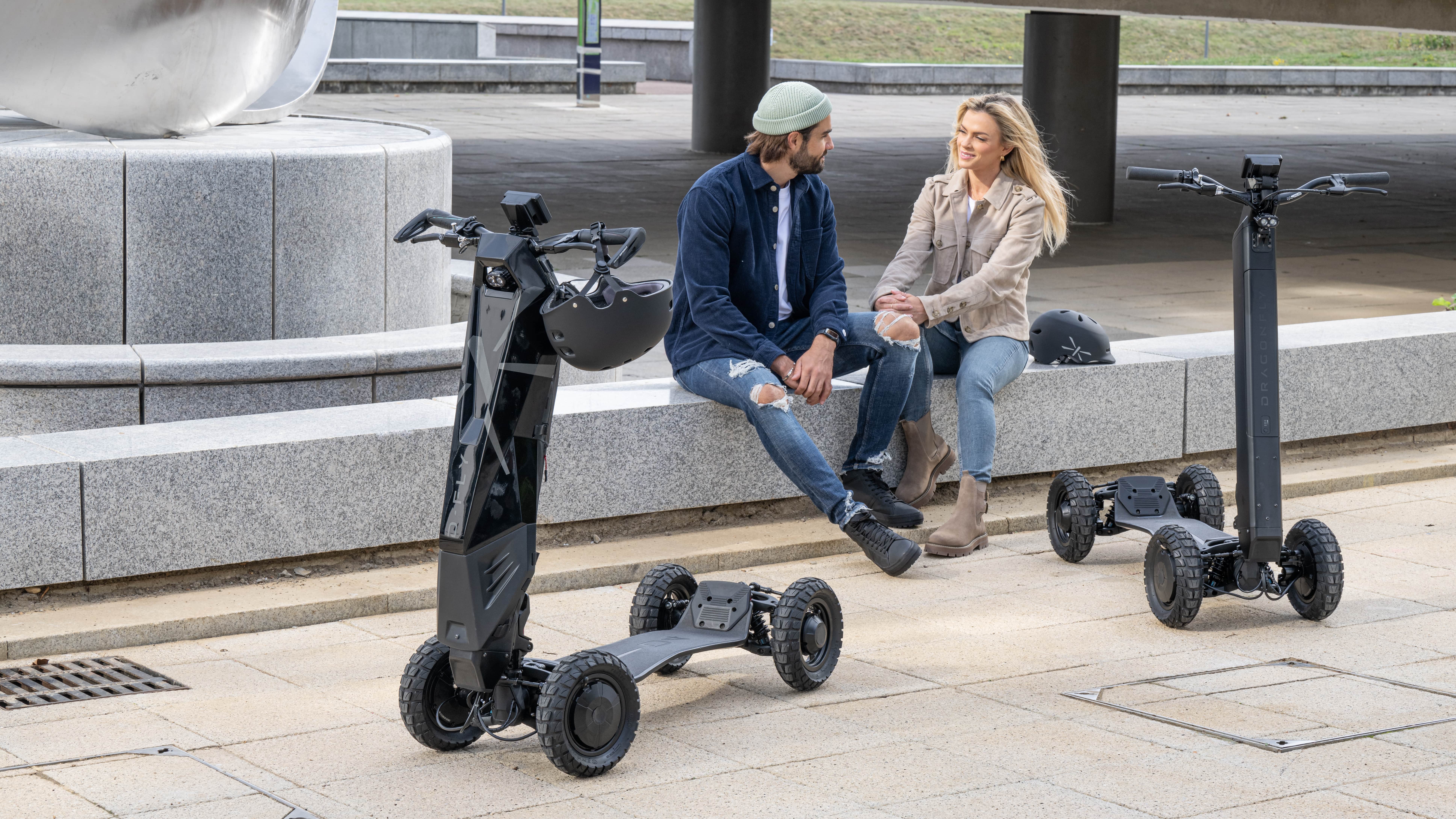 Two D-Fly Dragonfly electric scooters parked in the street