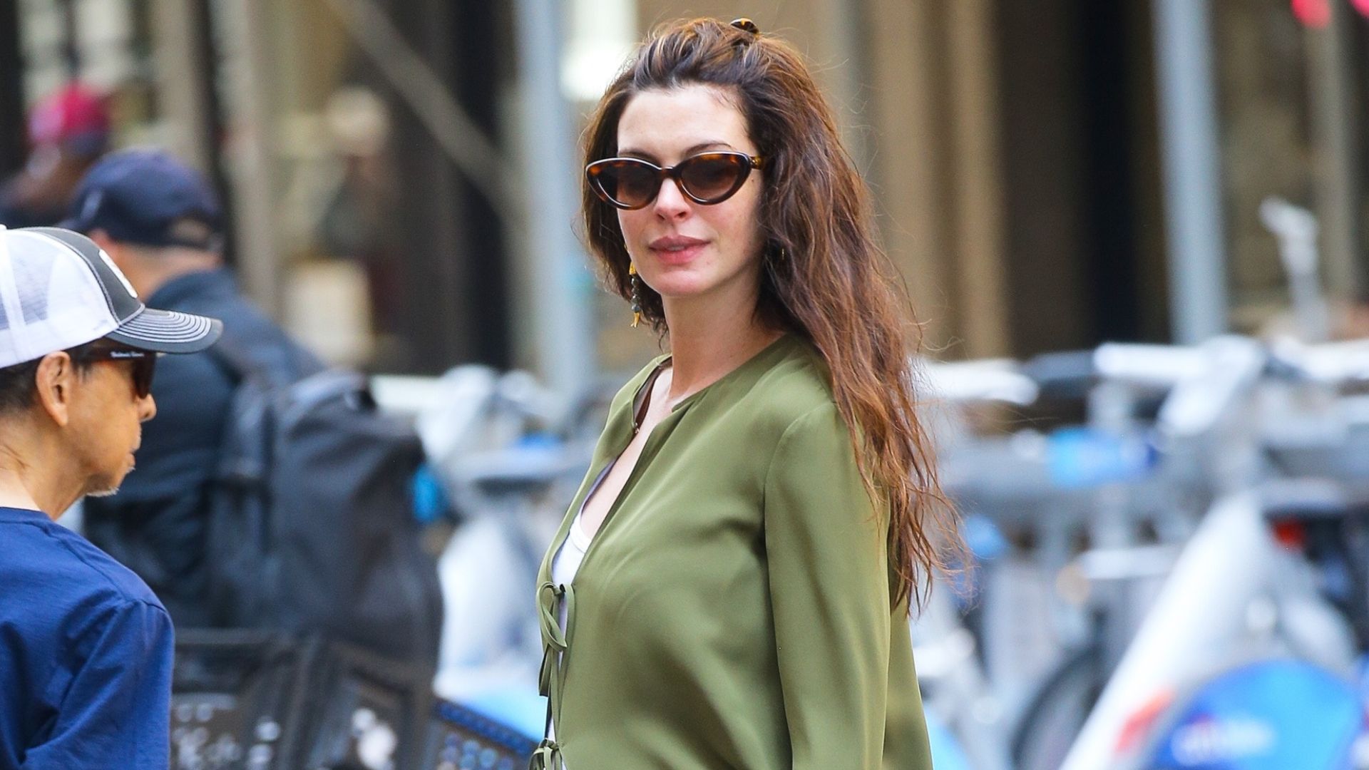 Anne Hathaway wears mesh ballet pumps with green floral trousers and a maxi cardigan.