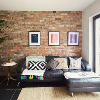 sitting area with brick wall and black sofa with cushions