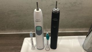 Two clean electric toothbrushes with heads removed sitting on a sink